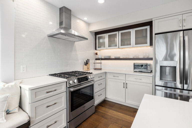 White kitchen with subway tile backsplash, stainless gas range and hood, and glass-front cabinets over open shelving