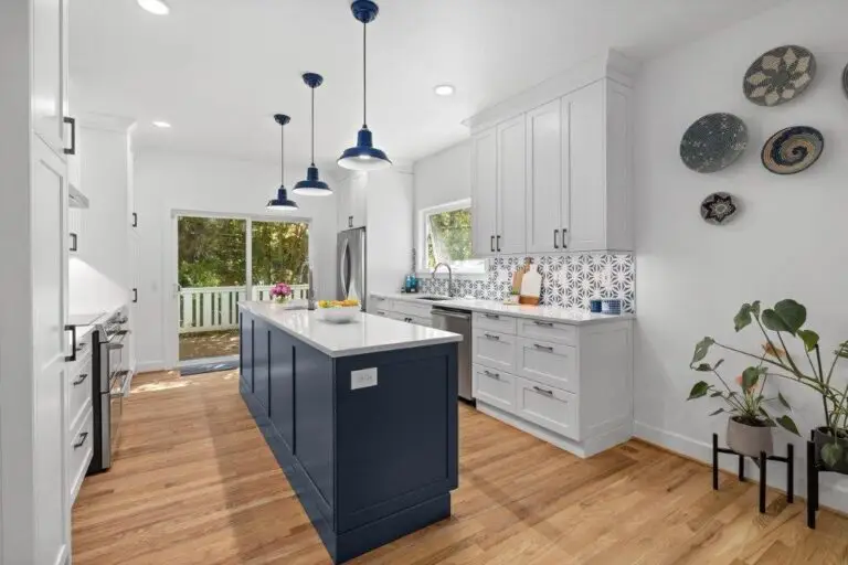 Navy blue island with white quartz top, blue barn pendants, patterned tile backsplash and woven wall baskets