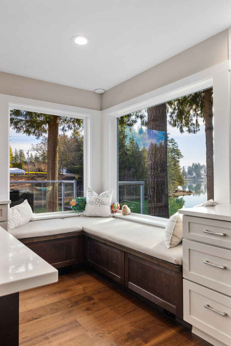 Corner window seat with storage bench and cushions overlooking the lake at a remodeled lakeside home