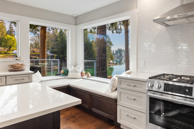 Kitchen breakfast nook with built-in window seat, lake views, and stainless gas range with white subway tile