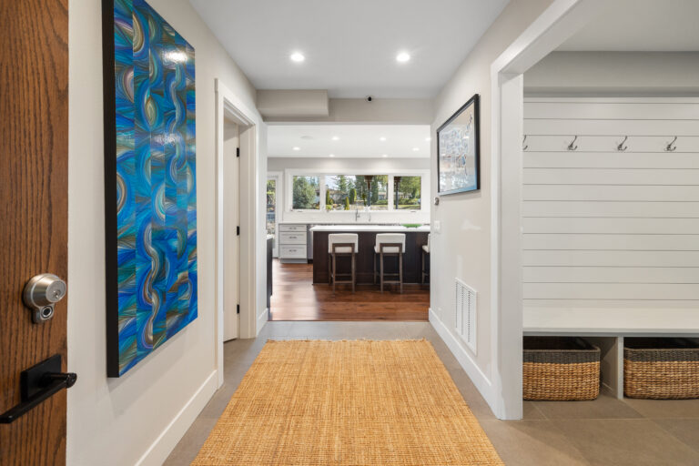 Entry hall with blue abstract art and jute runner leading to the kitchen island and shiplap mudroom