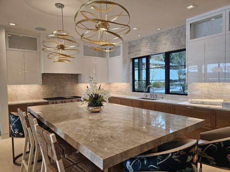 Kitchen island in taupe quartzite with gold glass pendants and matching full-height stone backsplash