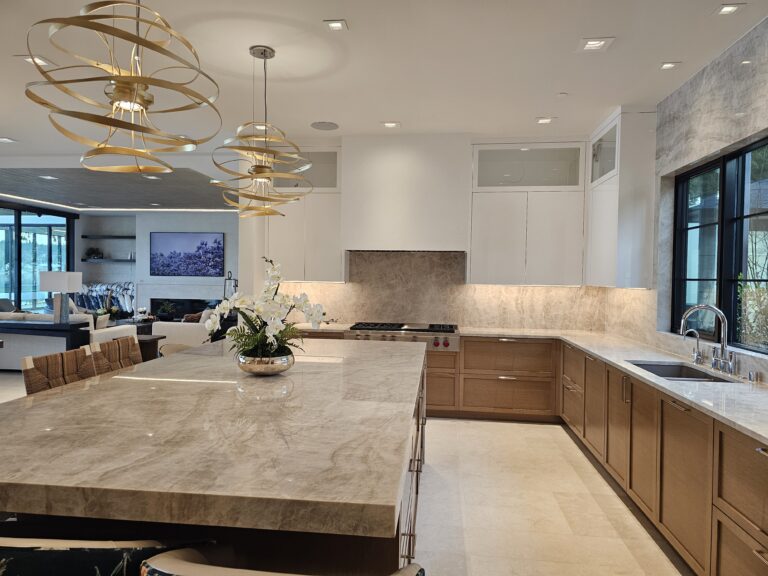 Open-plan kitchen with taupe quartzite island and backsplash, flowing into a bright seating area