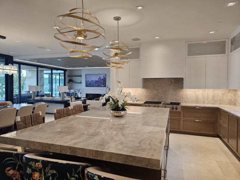 View across the quartzite island toward the living room, with woven counter stools and an orchid