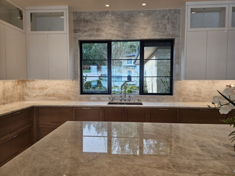 Kitchen sink wall with black-framed windows and taupe quartzite counters and backsplash