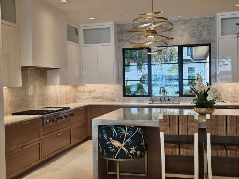 Corner of the quartzite island with a floral stool, gold pendant, and rangetop wall behind