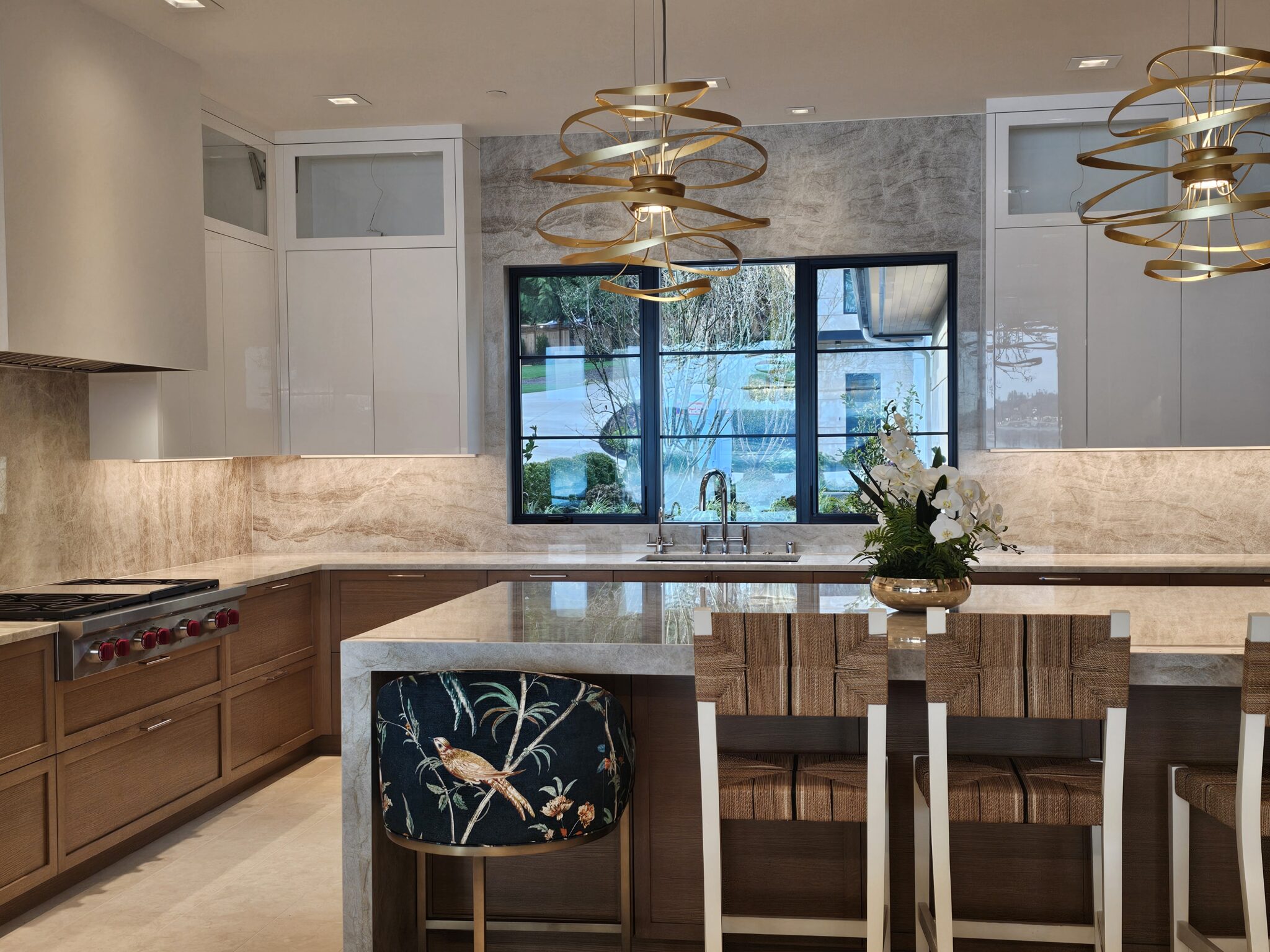 Quartzite island with upholstered counter stools facing the sink window wall