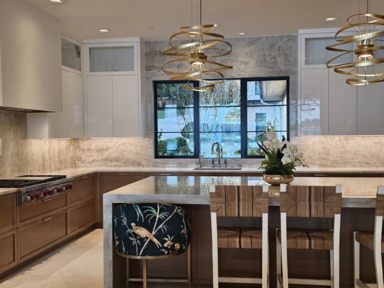 Quartzite island with upholstered counter stools facing the sink window wall