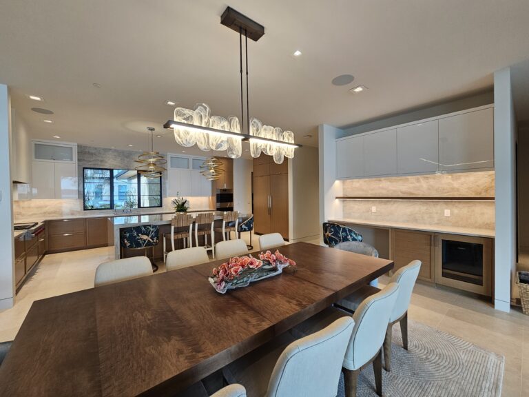 Dining area with wood table and linear glass chandelier adjoining the quartzite kitchen