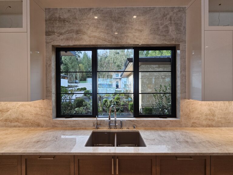Kitchen sink in quartzite with full-height slab surround at the black-framed window