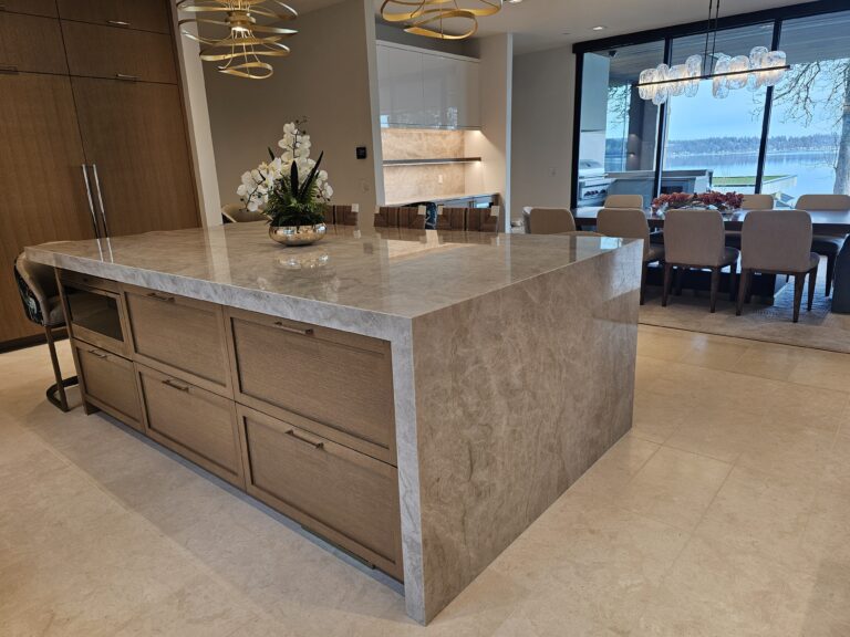 Quartzite waterfall island with built-in microwave, dining table and lake view beyond
