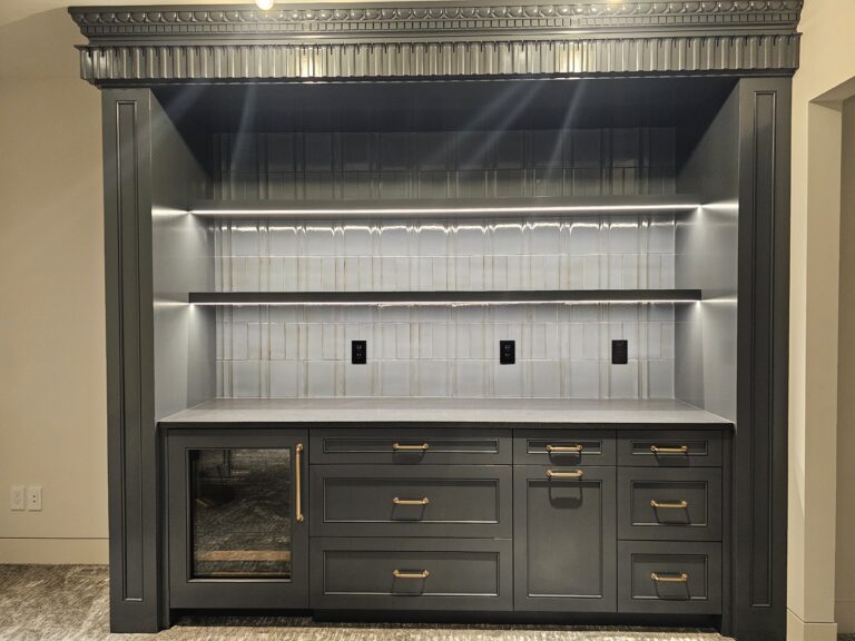 Charcoal bar cabinetry with beverage fridge, gray quartz counter, and backlit tile niche