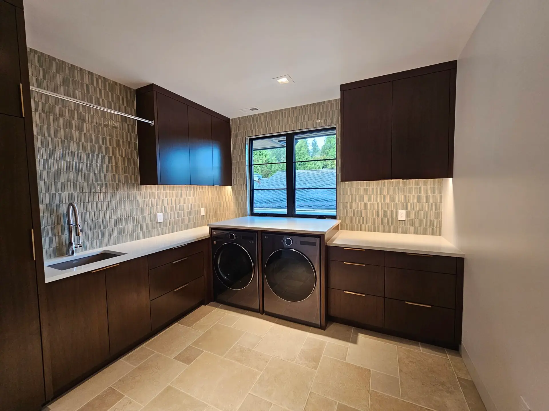 Laundry room with quartz folding counter over the washer and dryer and stacked mosaic backsplash