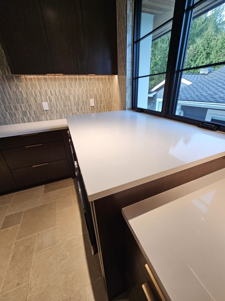 White quartz folding counter spanning the washer and dryer beneath the laundry room window