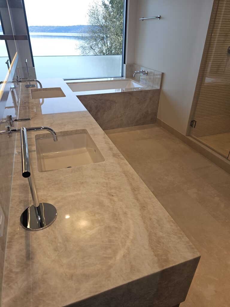 Quartzite slab backsplash and wall-mounted faucet detail in the primary bathroom