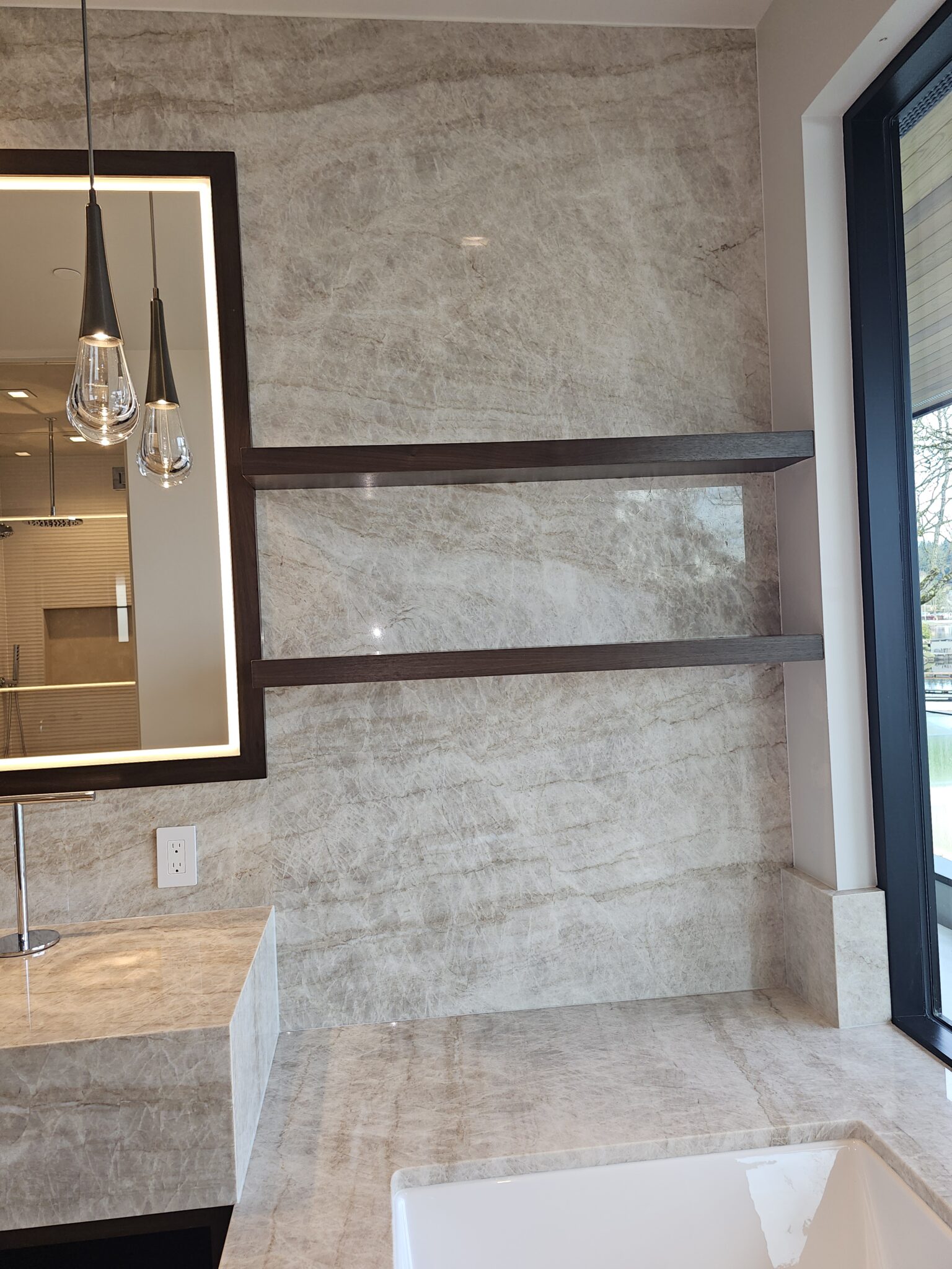 Floor-to-ceiling taupe quartzite slab walls beneath a skylight in the primary bathroom