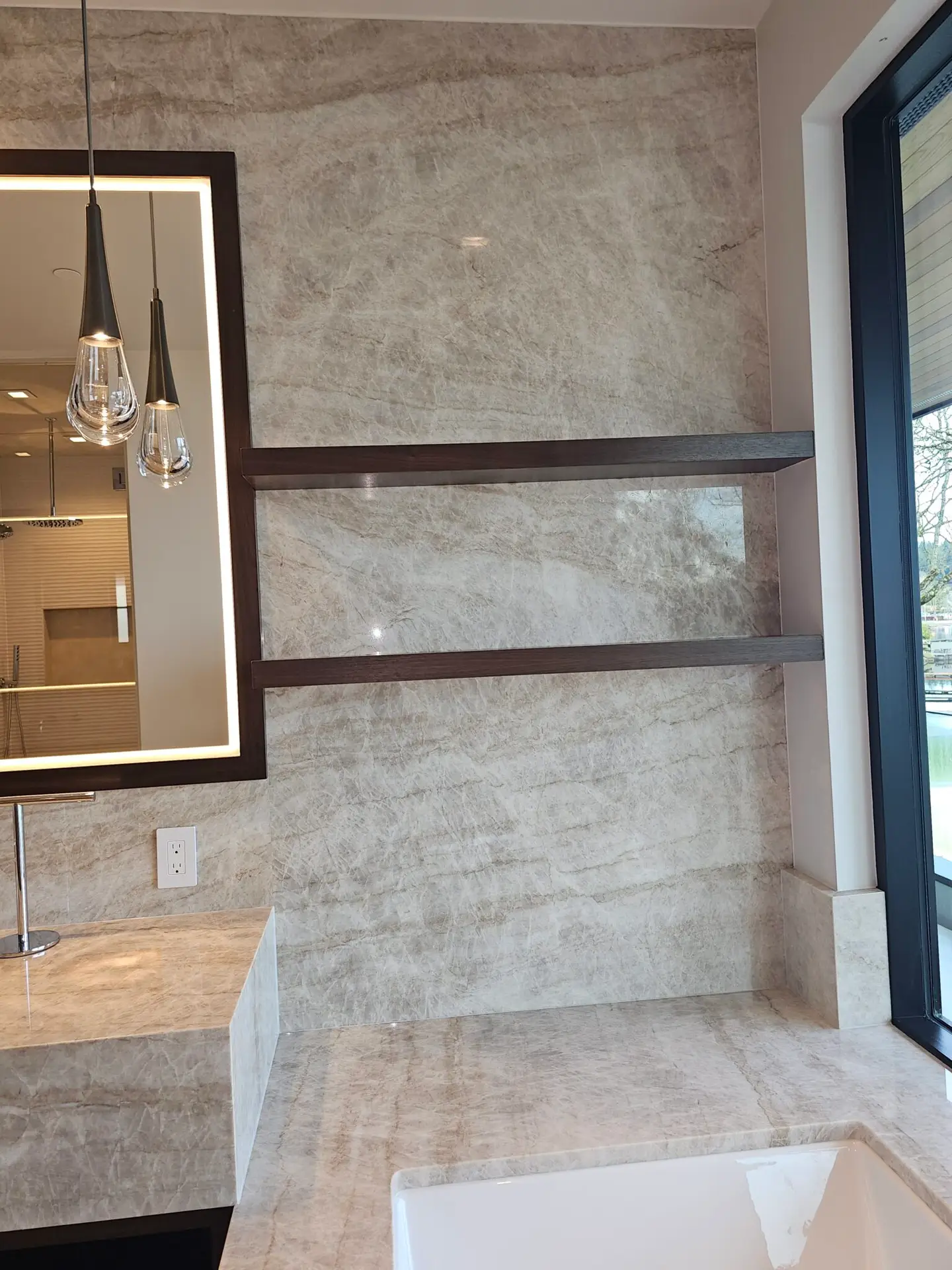Floor-to-ceiling taupe quartzite slab walls beneath a skylight in the primary bathroom