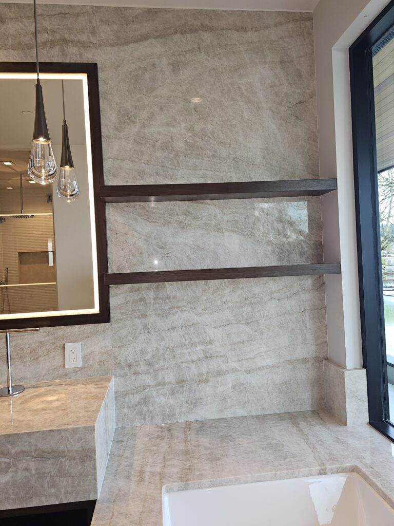 Floor-to-ceiling taupe quartzite slab walls beneath a skylight in the primary bathroom
