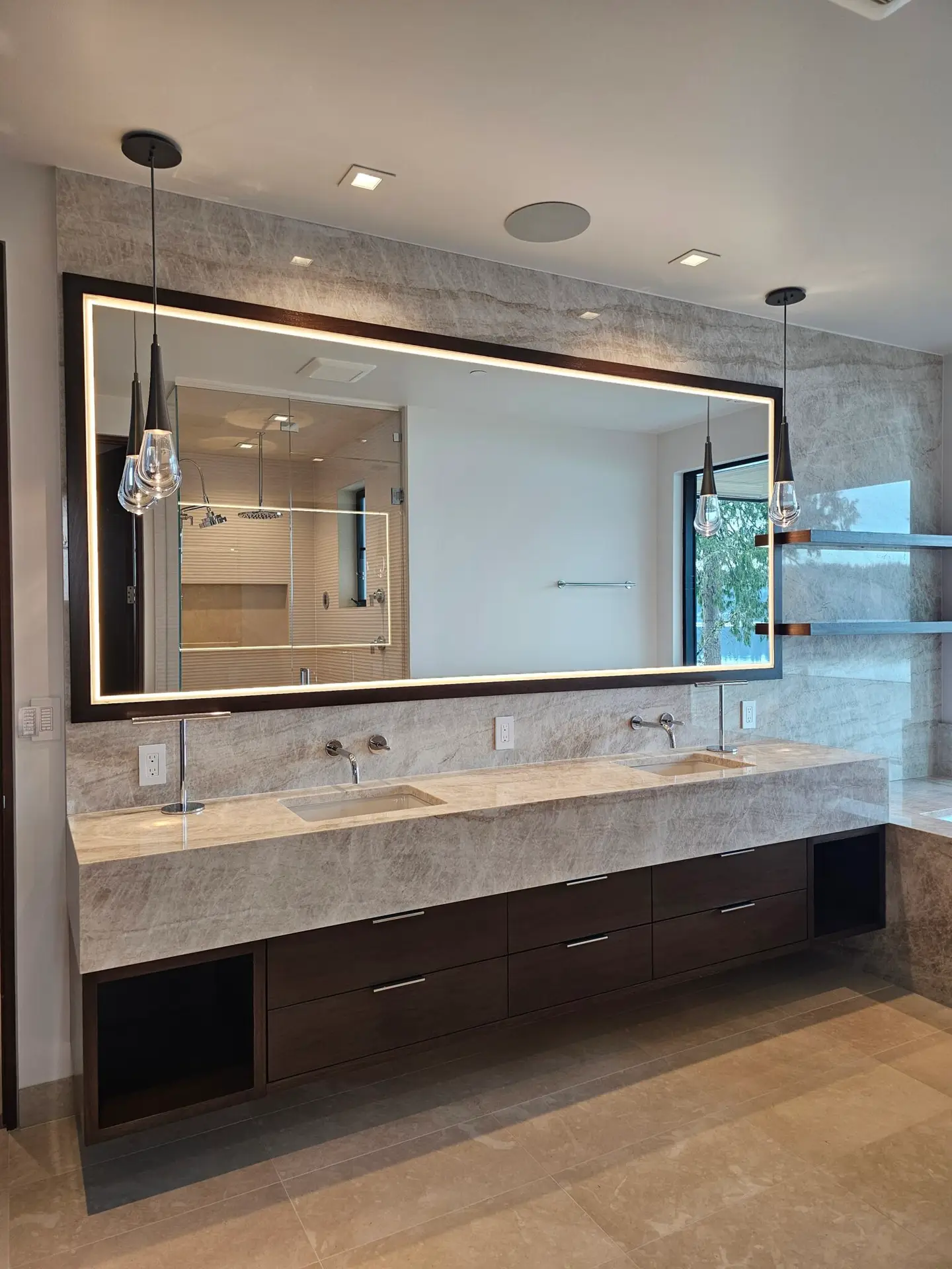 Backlit mirror and quartzite vanity wall in the primary bath with skylight overhead