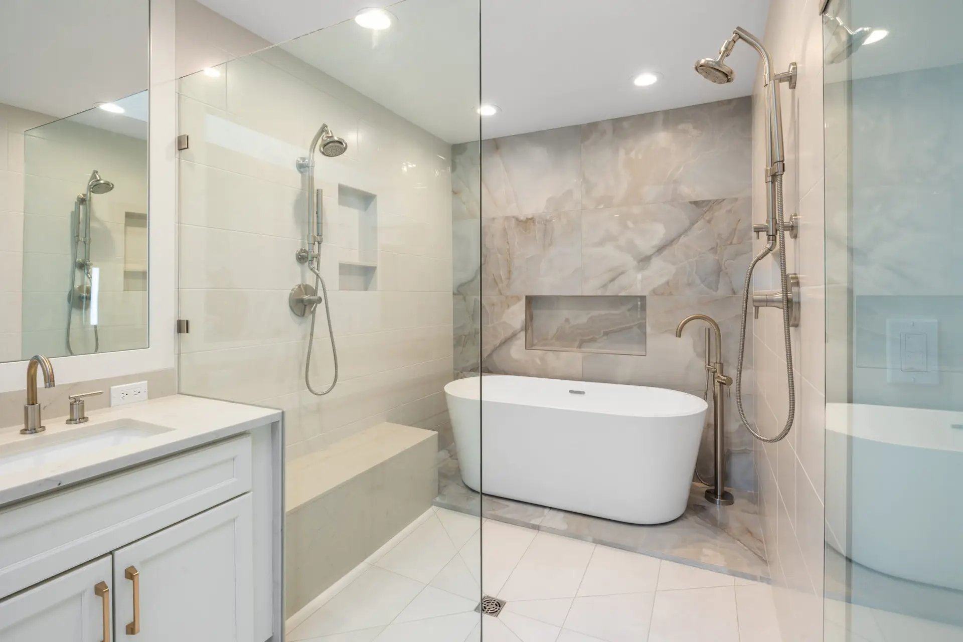 Wet room detail of freestanding soaking tub, floor-mounted tub filler, and marble-look porcelain accent wall
