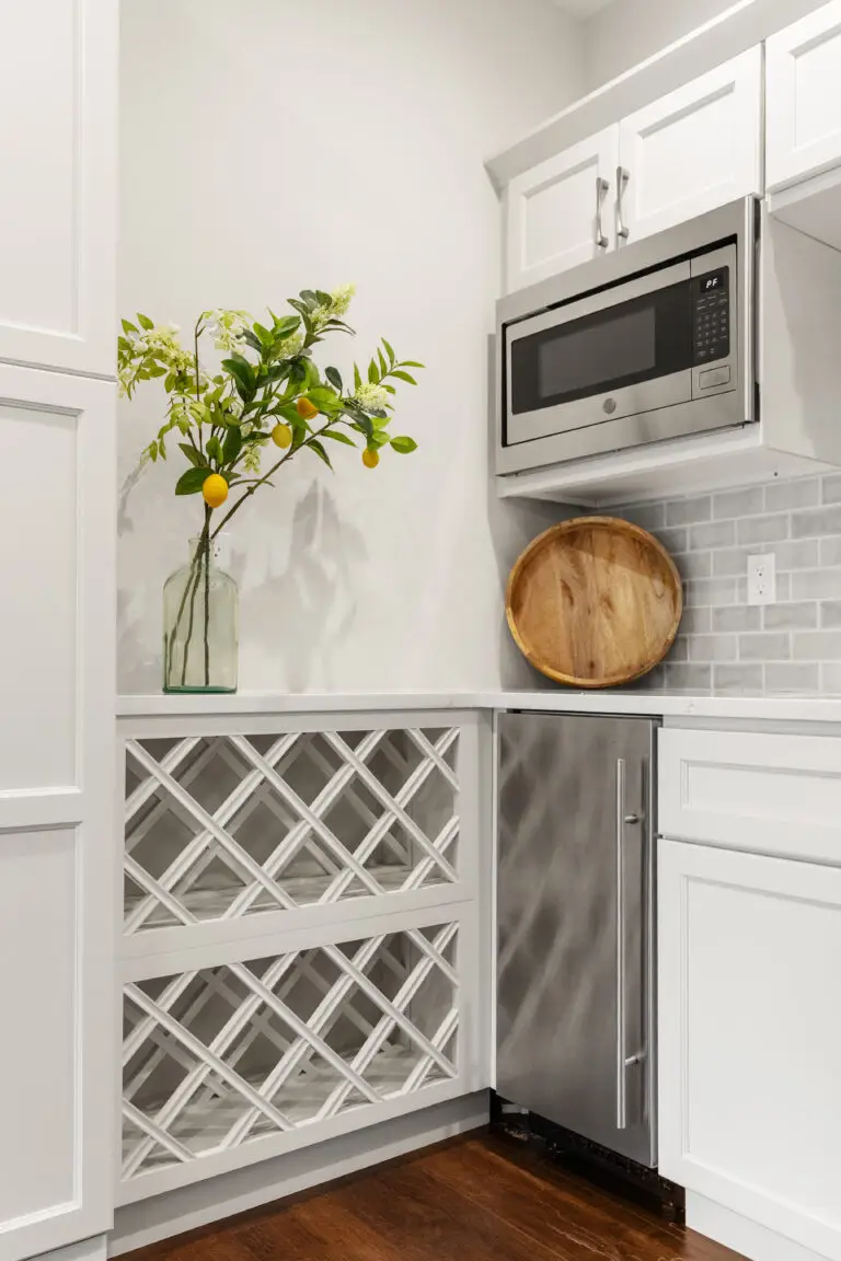 Butler pantry corner with built-in lattice wine rack, stainless microwave, and beverage refrigerator