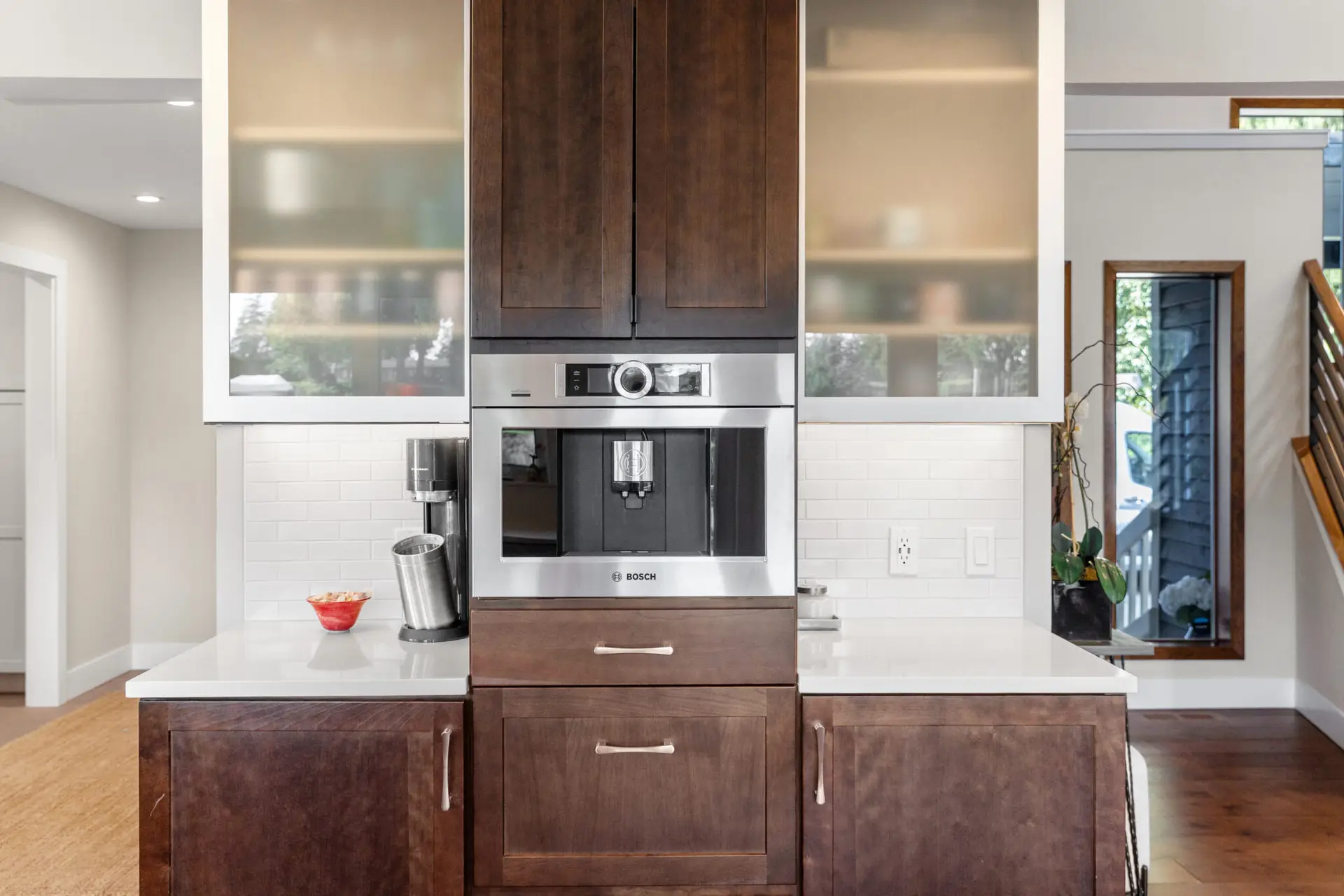 Built-in coffee machine centered in dark wood cabinetry between frosted glass display cabinets