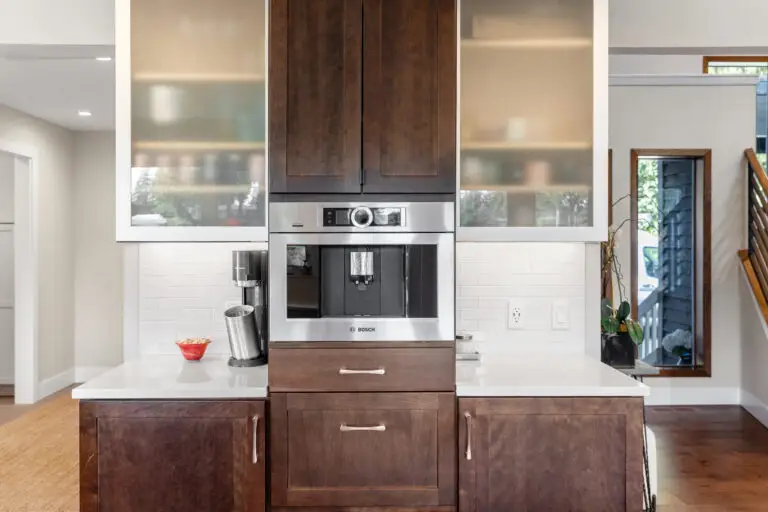 Built-in coffee machine centered in dark wood cabinetry between frosted glass display cabinets