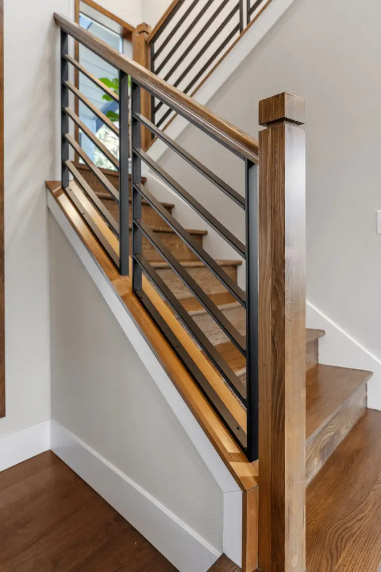 Staircase detail with warm wood handrails, square newel posts, and black horizontal metal balusters