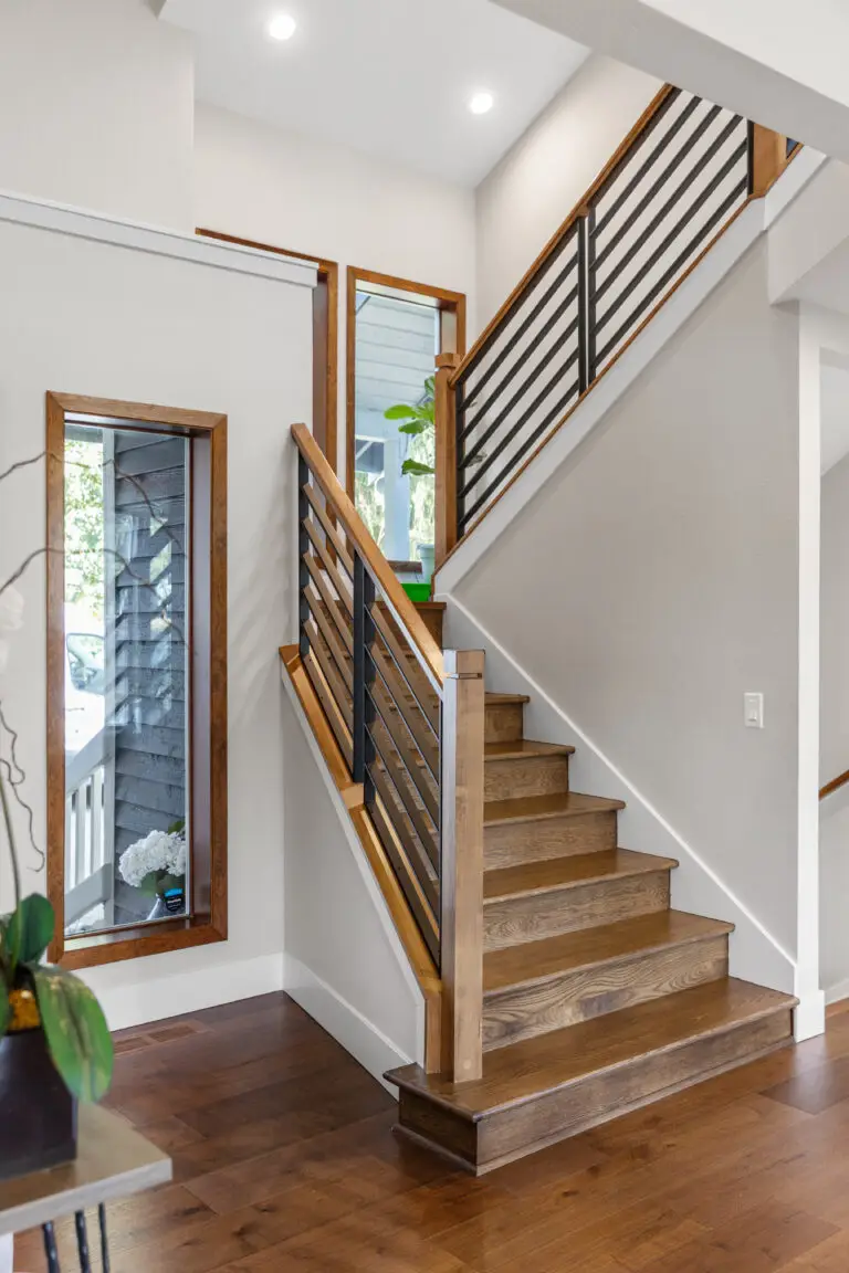 Wood staircase with black horizontal metal railing and oak treads in a bright remodeled entry