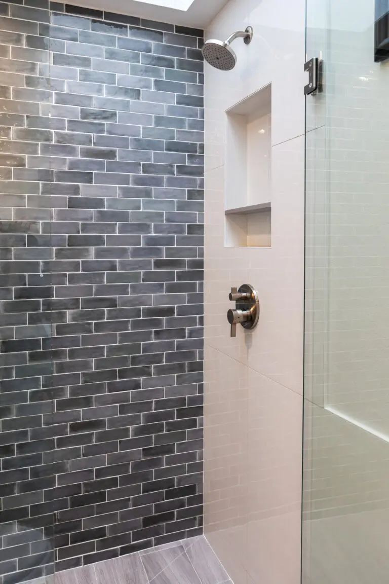 Walk-in shower with glossy gray subway tile accent wall, white tile, and brushed nickel rain shower head