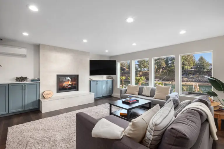 Family room with tiled fireplace, blue-gray built-in cabinets, and big windows overlooking the water