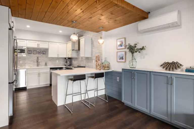Kitchenette with dusty blue lower cabinets, white quartz counters, shiplap peninsula, and gray subway tile