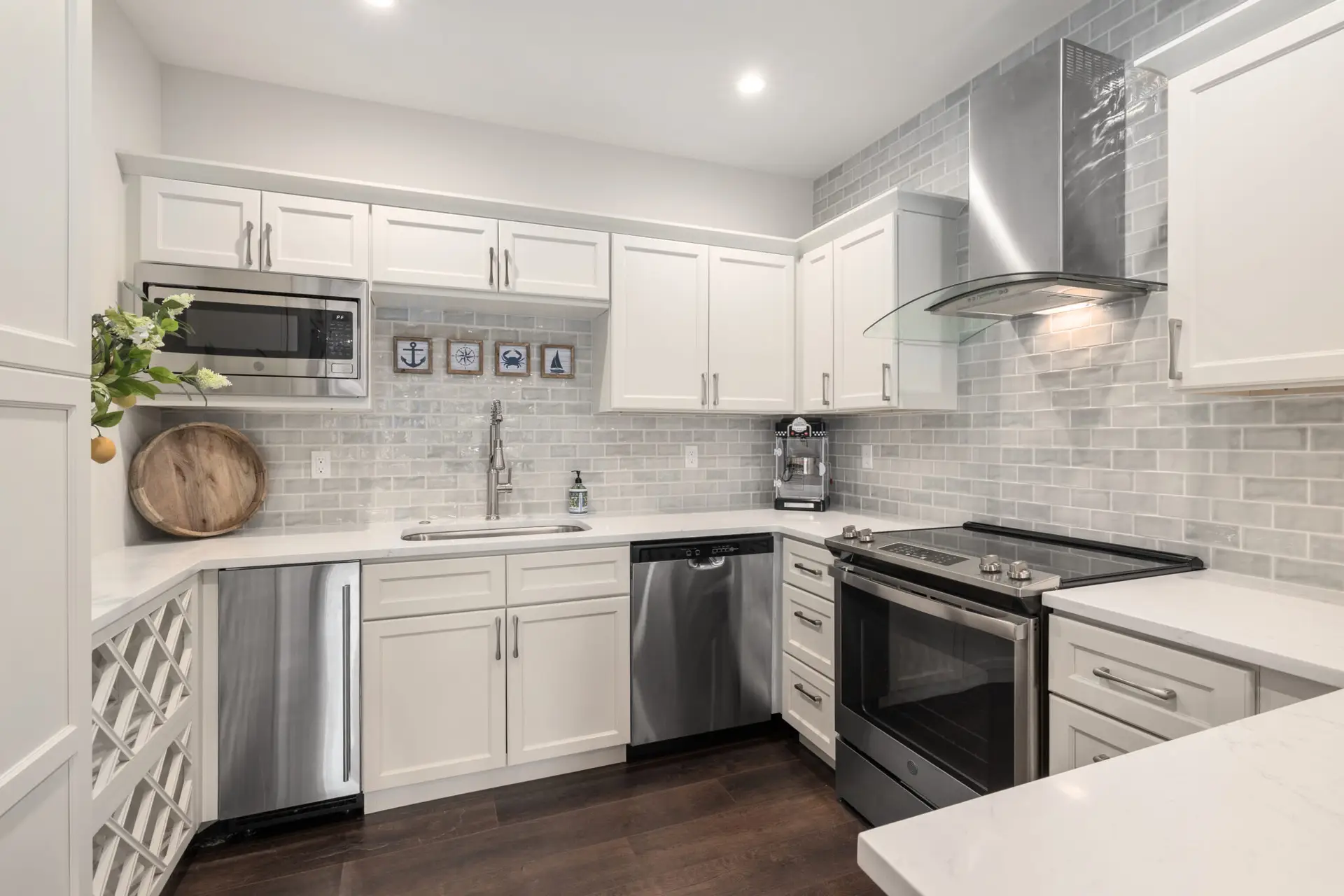 White kitchen with gray subway tile backsplash, stainless range, dishwasher, and curved glass hood