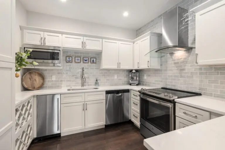 White kitchen with gray subway tile backsplash, stainless range, dishwasher, and curved glass hood