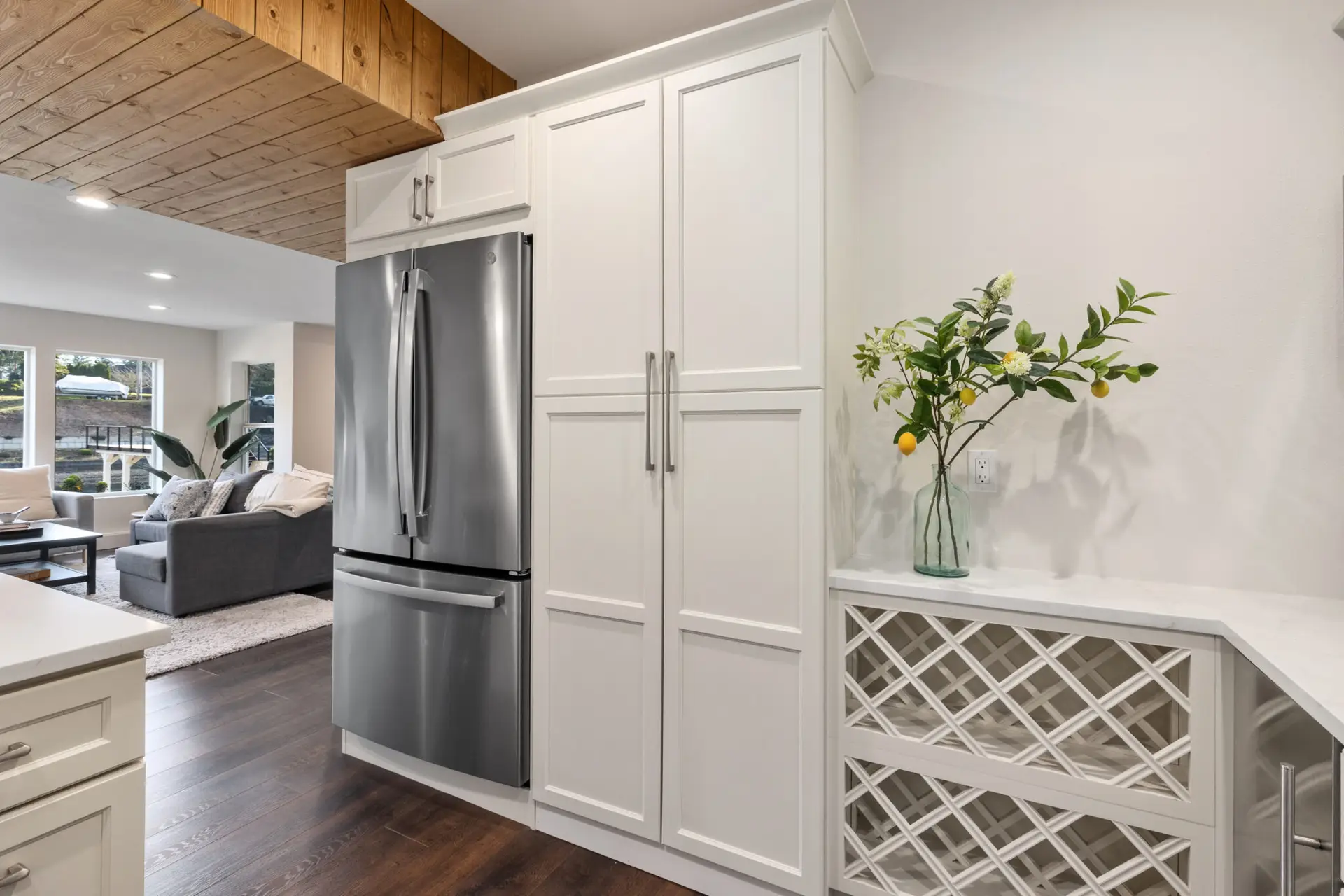 Stainless french-door refrigerator flanked by white pantry cabinets and a lattice wine rack