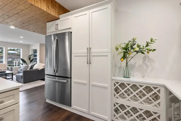 Stainless french-door refrigerator flanked by white pantry cabinets and a lattice wine rack