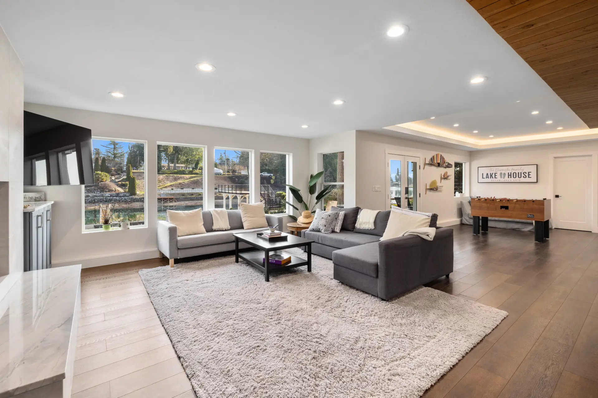 Family room with sectional seating, lake house sign, foosball table, and water-view windows