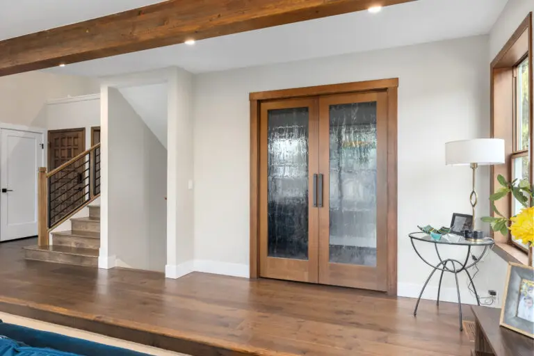 Entry hall with wood-framed rain-glass double doors, wide-plank hardwood, and staircase with metal railing