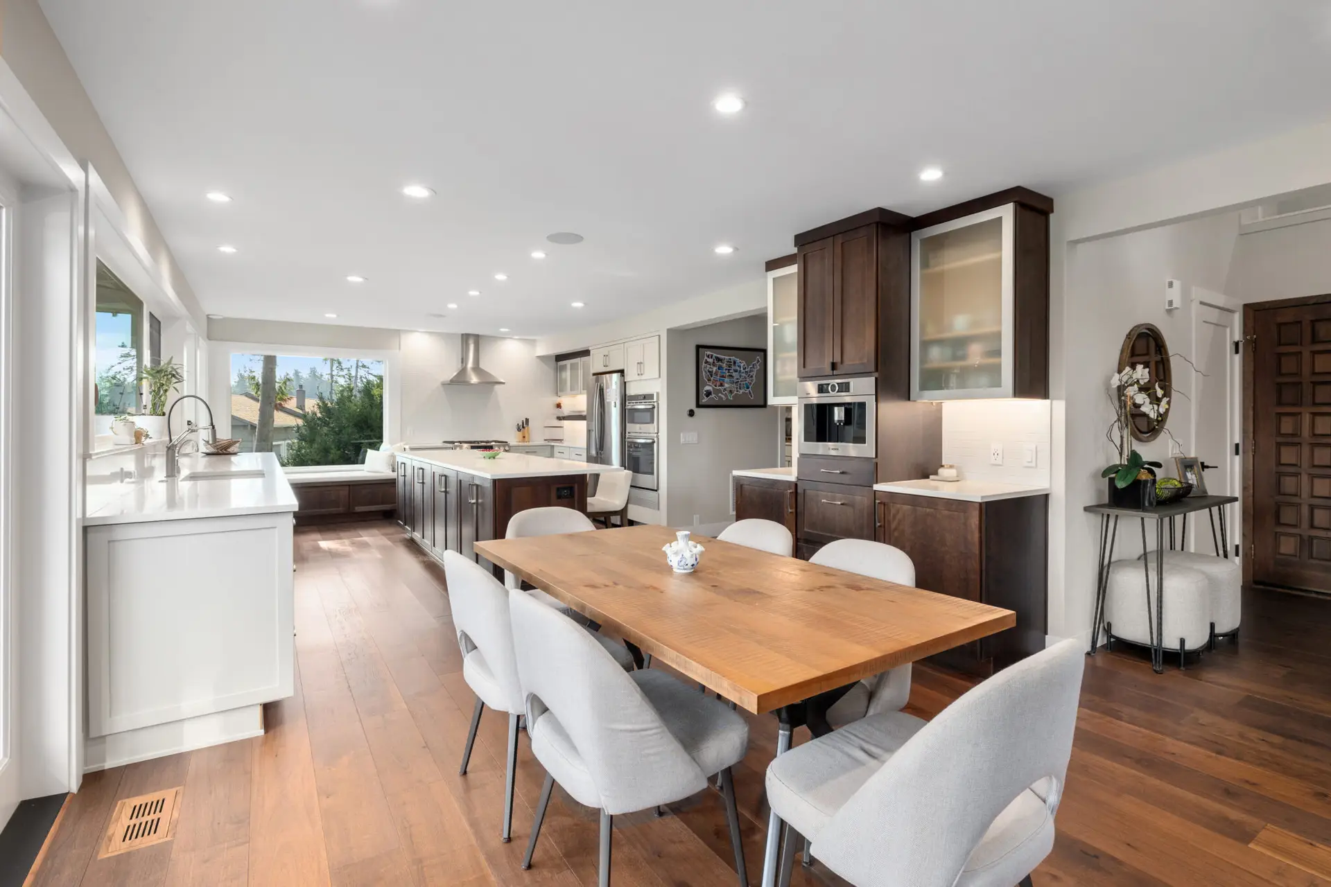 Open kitchen and dining space with rustic wood table, dark wood cabinetry, and built-in coffee station