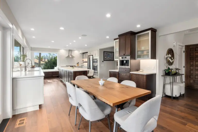 Open kitchen and dining space with rustic wood table, dark wood cabinetry, and built-in coffee station