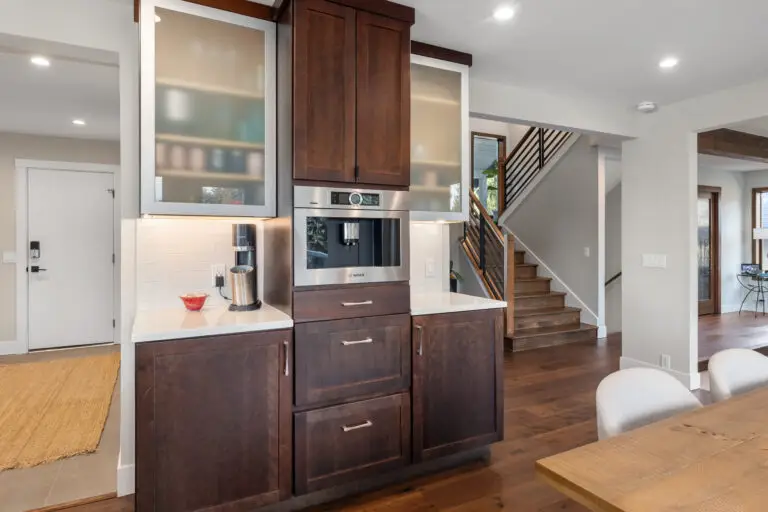 Dark wood coffee bar with built-in Bosch machine, frosted-glass uppers, and staircase beyond