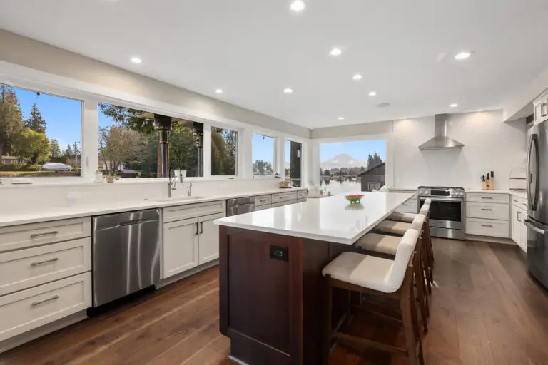 Remodeled kitchen with long white quartz island on dark wood base, bar seating, and lake and mountain views
