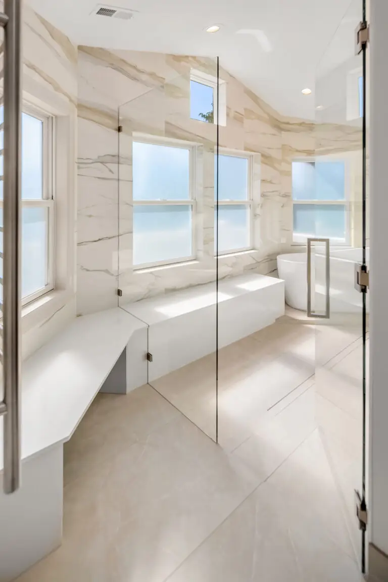 Glass shower with quartzite bench, frosted windows and freestanding tub in the remodeled bathroom