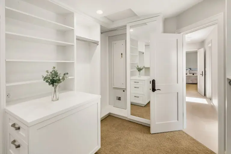 White walk-in closet with full-length mirror, built-in safes and door opening to the bedroom