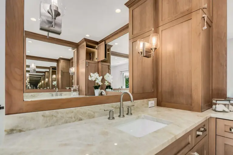 Mirrored vanity wall and cherry cabinet tower with concealed appliance storage and glass sconces