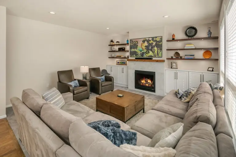 Cozy family room with sectional, leather armchairs, wood coffee table, and fireplace flanked by built-ins