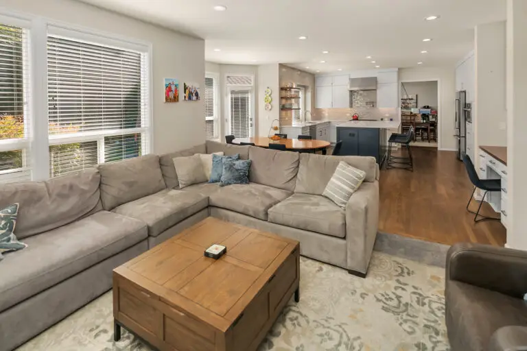 Gray sectional and wood coffee table in a family room open to the remodeled kitchen with navy island