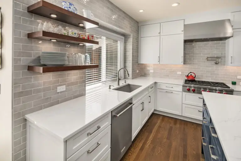 Kitchen sink wall with floating walnut shelves, glossy gray Cloe tile backsplash, and stainless dishwasher