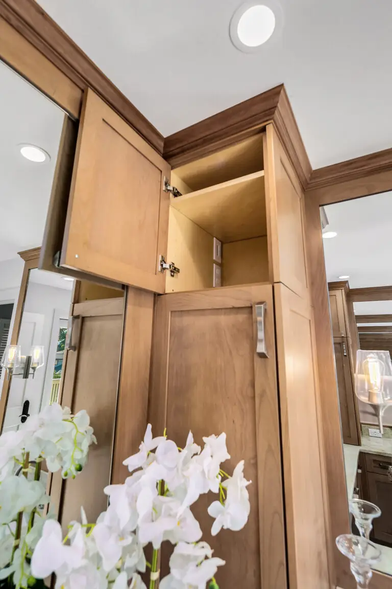 Upper cherry cabinet open to reveal a hidden outlet compartment above the vanity