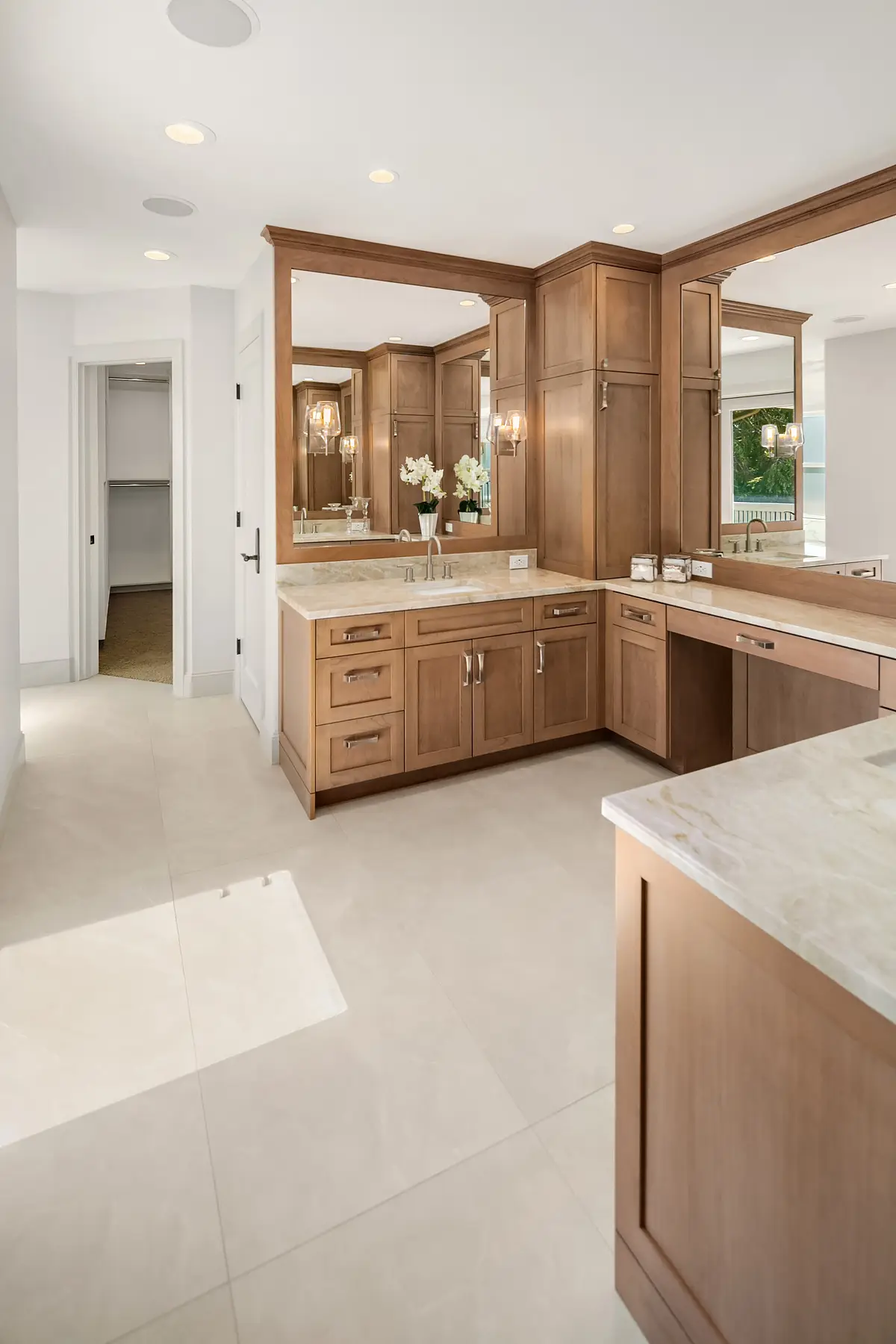Master bathroom with cherry vanities, Taj Mahal quartzite counters and hallway to the walk-in closet